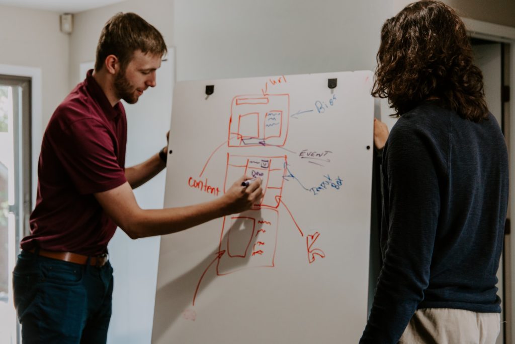 2 People drawing on a white board strategies about domain and page authority